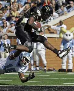 Josh Adams jumps over North Carolina's Kendrick Burney for a touchdown in the first quarter in Winston-Salem, N.C. on Saturday. (AP Photo/Chuck Burton)
