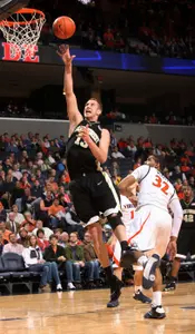 Virginia forward Mike Scott, right, watches as Wake Forest center Chas McFarland shoots . (AP)