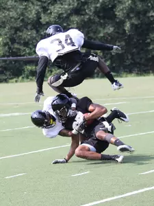 Duran Lowe (34) leaps high to avoid a collision with another defender and Orville Reynolds (27) at preseason practice on Friday, August 12.
