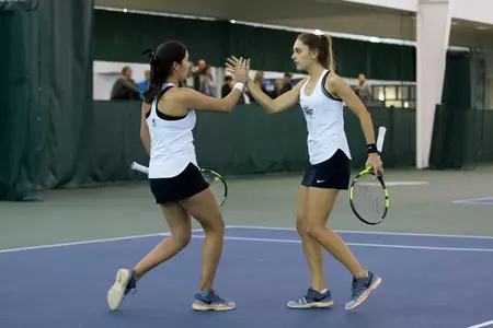 Alexis Franco (left) of the Wake Forest Demon Deacons slaps hands with double partner Eliza Omirou during their match against the Liberty Flames at the Wake Forest Indoor Tennis Center on March 11, 2017 in Winston-Salem, North Carolina. The Demon Deacons defeated the Flames 6-1. (Brian Westerholt/Sports On Film)