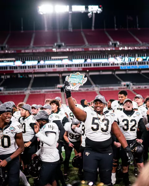 Photo of Je'Vionte' Nash smiling and holding up a sign with the 2022 Union Home Mortgage Gasparilla Bowl logo