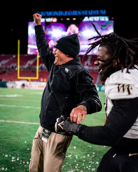 Photo of Coach Clawson celebrating with his arm in the air