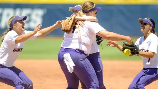 The Huskies hug in the circle after advancing to the WCWS championship round