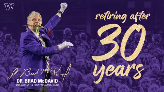 Photo of Dr. Brad McDavid directing the band with a rose in his mouth.