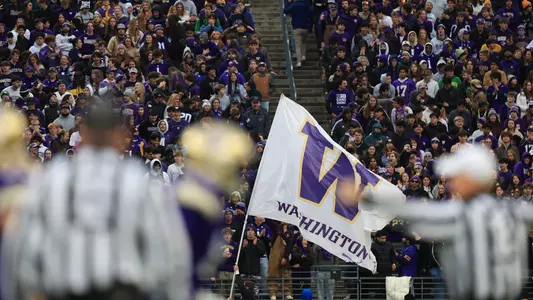 Washington W flag flies during game with students in stands behind it