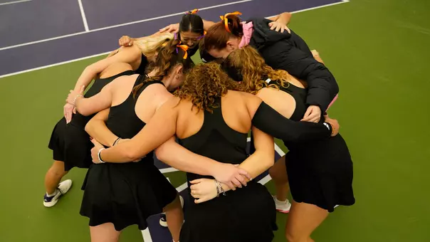 Women's tennis huddles as a team prior to match against Portland