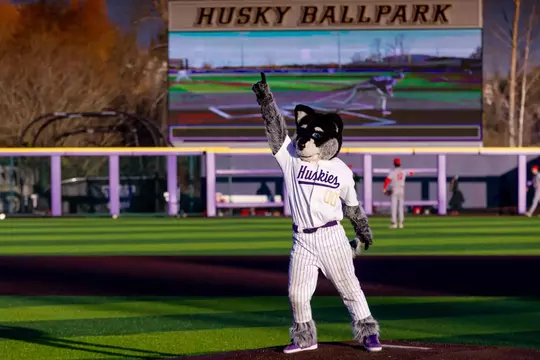 Harry points towards the sky while standing on baseball field
