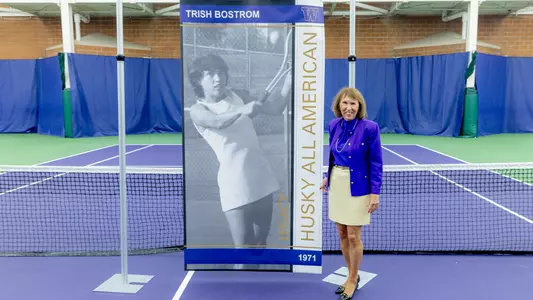 Trish Bostrom stands with her Legacy Husky All-American banner