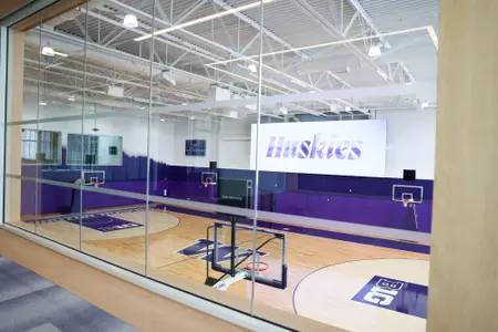 Husky Basketball Training Facility court shot with "Becoming" on videoboard