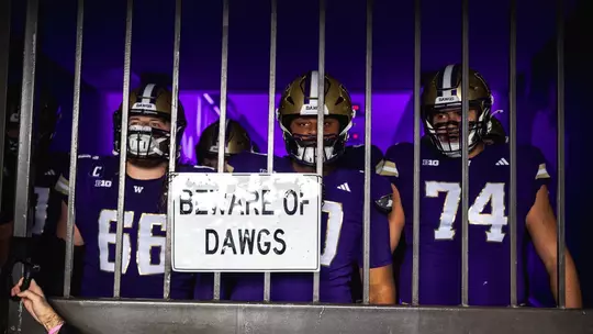 UW football players behind "Beware of Dawgs" sign