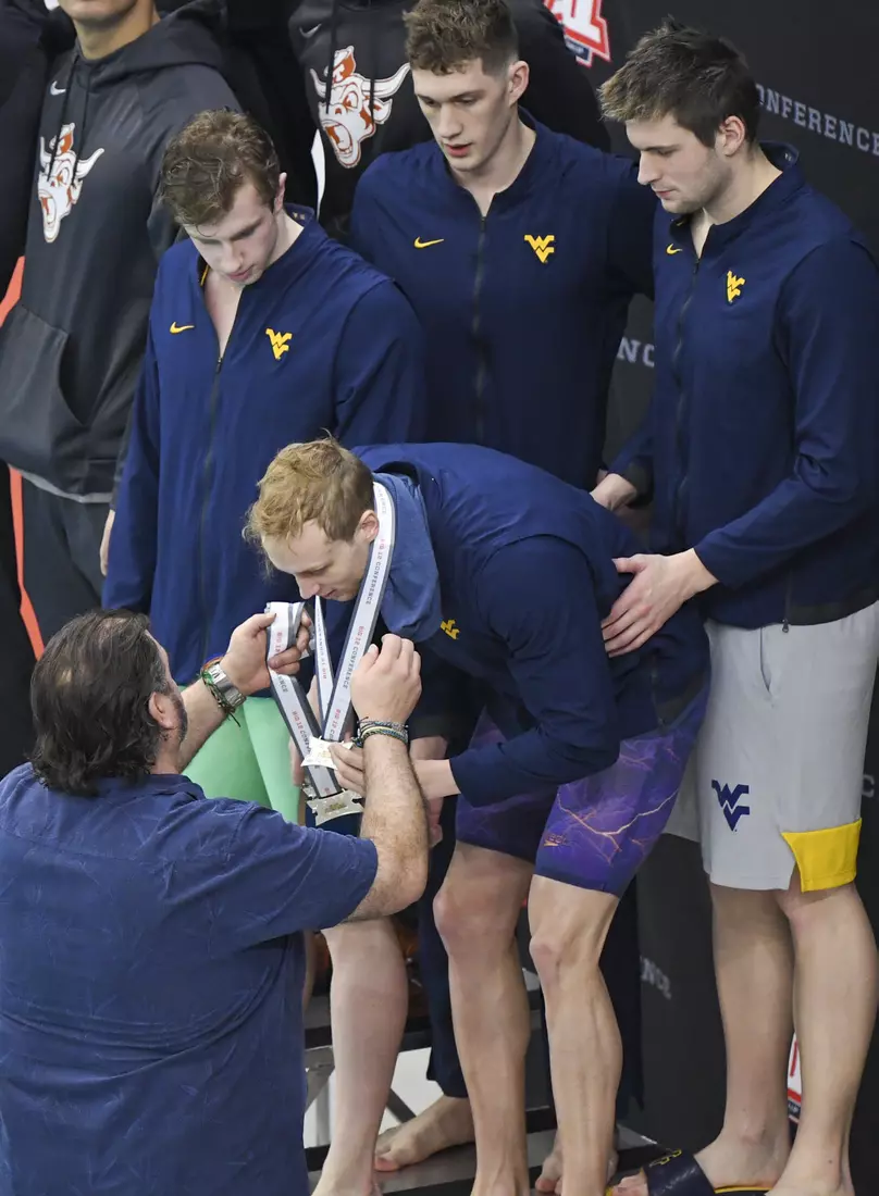 Vic Riggs awards third place medals to his men's 400 yard freestyle team.