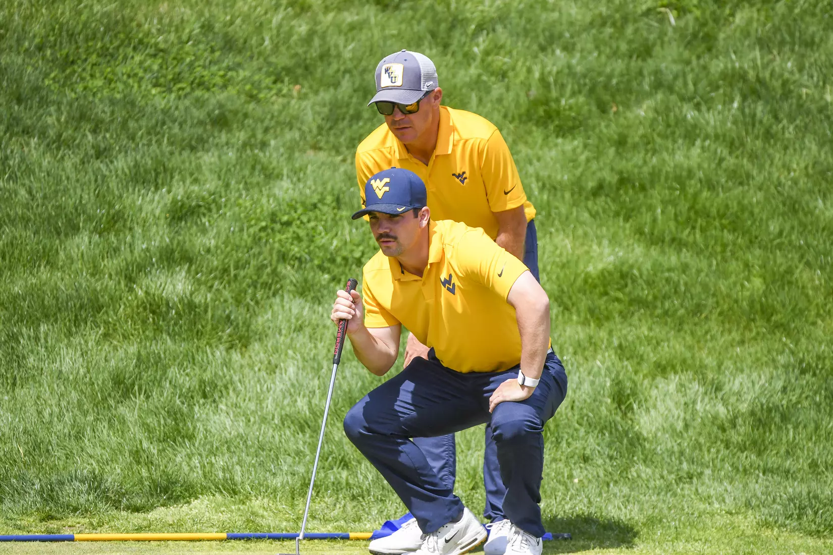 Etienne Papineau checks the line of a putt with head coach Sean Covich.