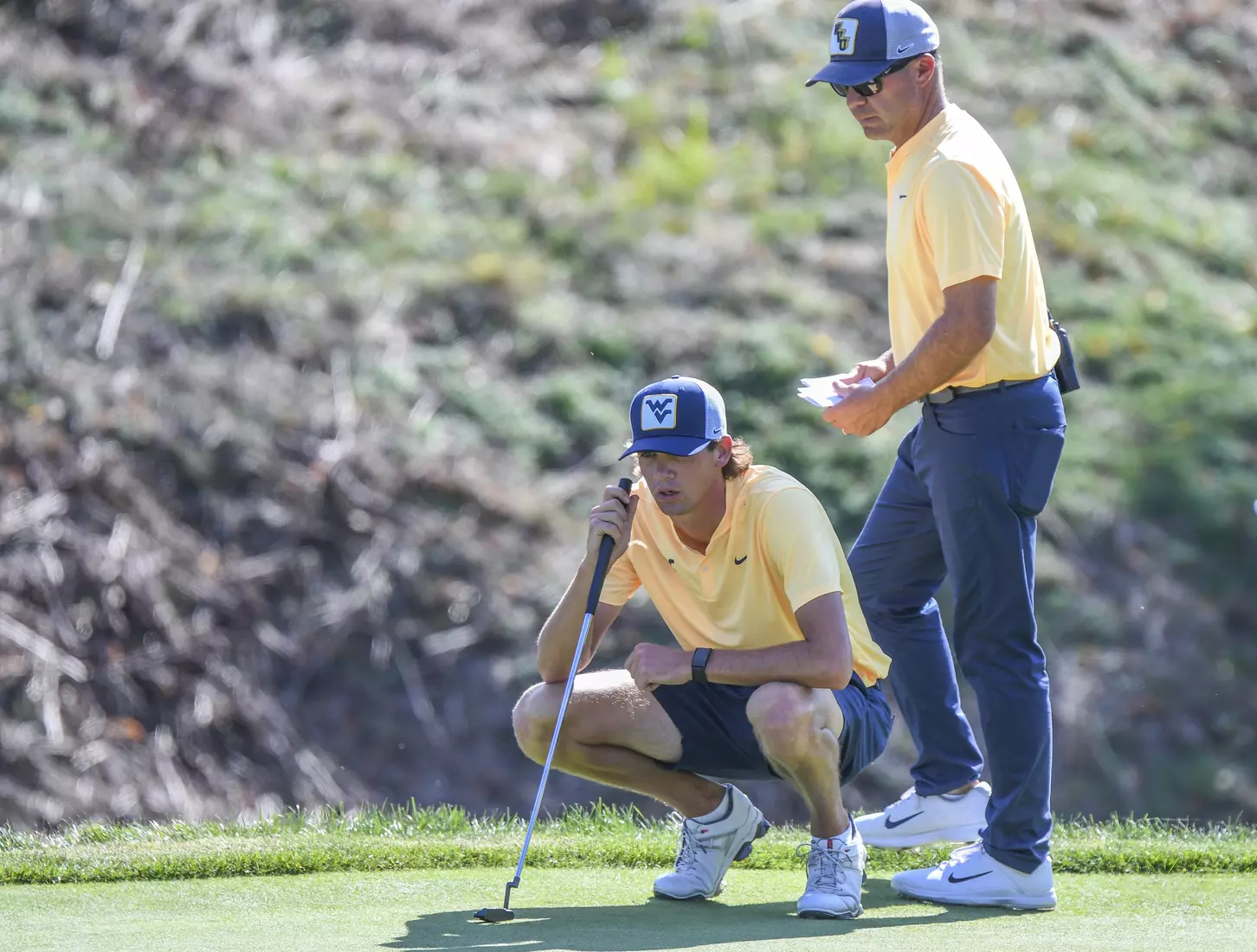 Coach Sean Covich and Mark Goetz look over Goetz's birdie putt on 18.