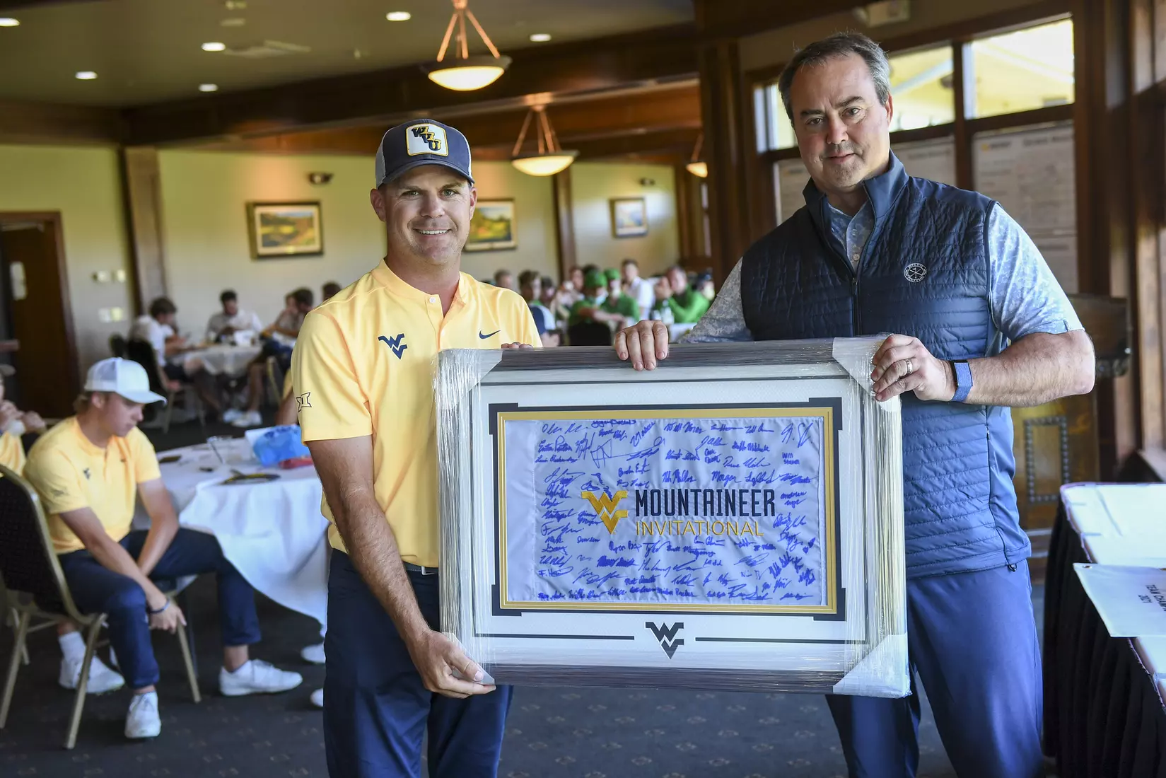 Coach Sean Covich presents a framed golf flag to Pete Dye Pro Chris McGinnis.