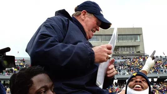 Players carry coach Don Nehlen off the field during his final game coaching at Mountaineer Field against East Carolina in 2000.