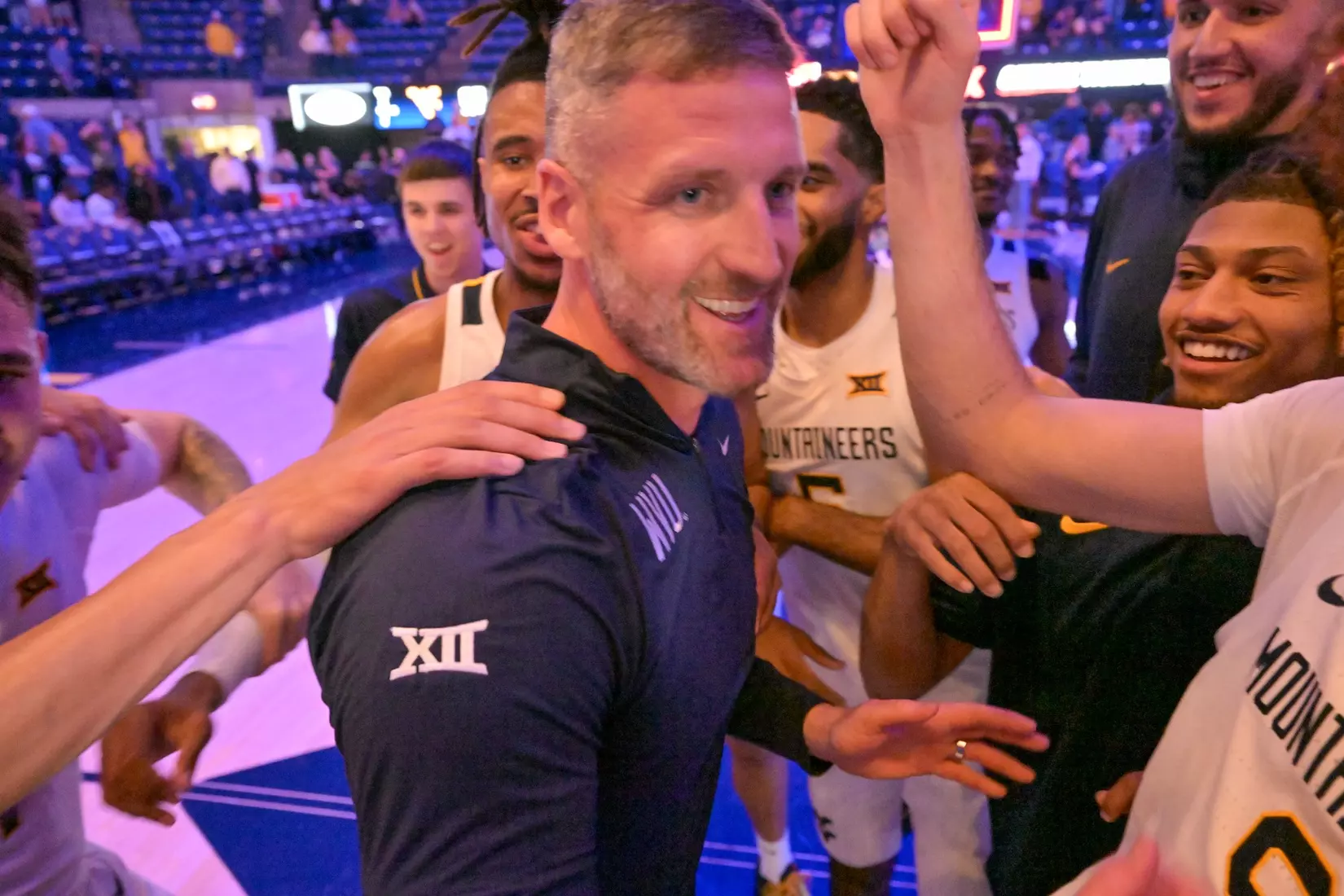 Head coach Josh Eilert is congratulated by his team on the court for his first ever win.