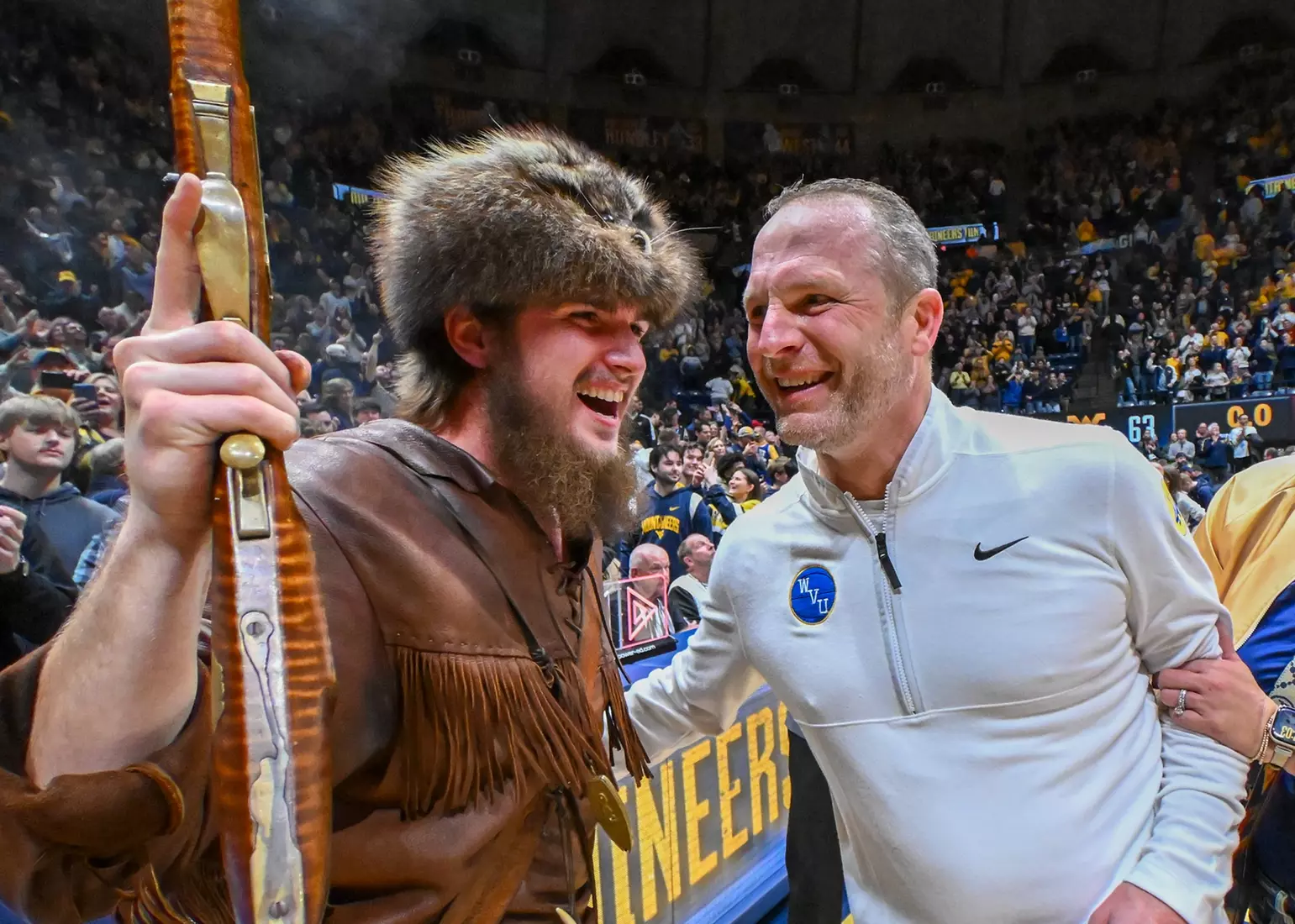 The Mountaineer mascot Braden Adkins celebrates with head coach Darian DeVries.
