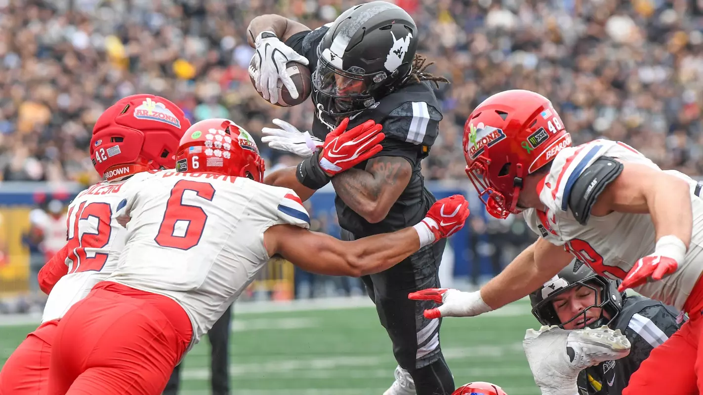 Running back Cam Cook leaps over the pile to score a touchdown in West Virginia's 52-31 loss to Arizona Saturday afternoon at Milan Puskar Stadium.