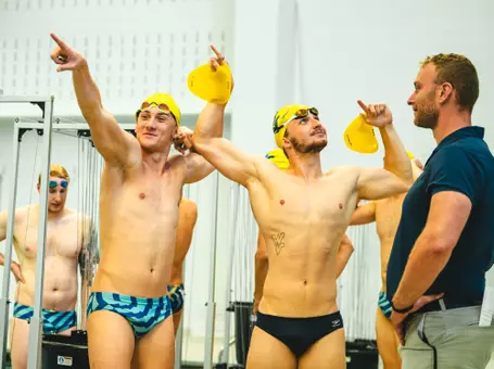 Two WVU men's swimmers flex their muscles while at practice.