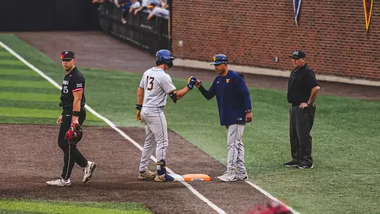 Ryan Maggy fist bumps first base coach Jacob Garcia after hitting a single.