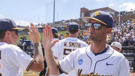 Coach Steve Sabins high-fives a West Virginia University player following the Mountaineers' Super Regional-clinching victory over Cal Poly on June 6, 2026, at Kendrick Family Ballpark in Granville, West Virginia.