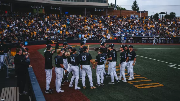 The WVU Baseball Team stands outside the dugout ready to take the field.