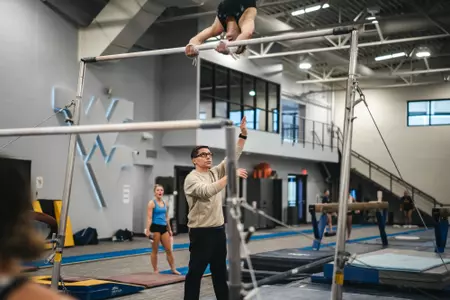 WVU gymnastics coach Jason Butts assists an athlete during practice at Cary Gym in Morgantown