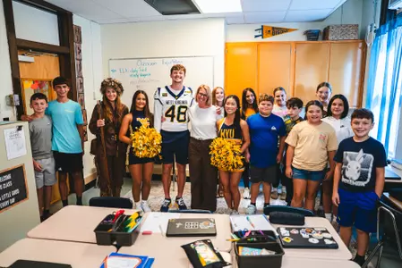 A group of WVU cheerleaders, students and football student-athlete Nate Flower celebrate Extra-Yard-For-Teachers-2026 program