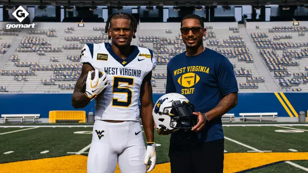 Jaden Bray (left) and Pat White (right) stand together on Mountaineer Field at Milan Puskar Stadium.