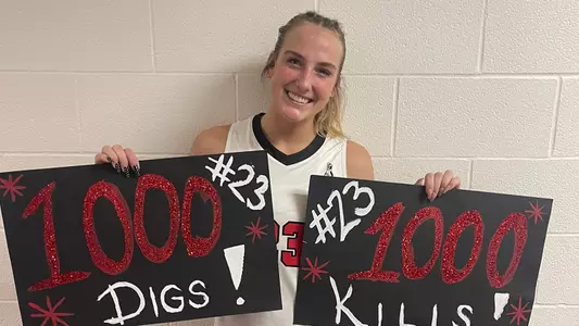 Abbie Householder holding two signs commemorating 1,000 career kills and 1,000 career digs
