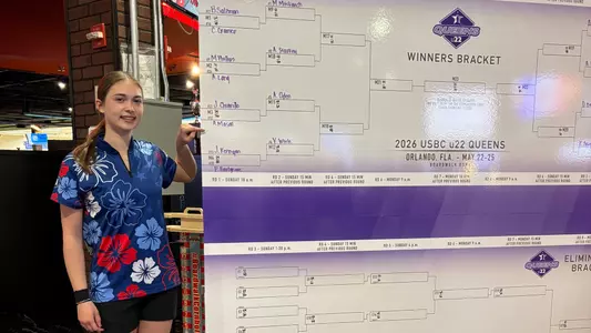 Amber Mason points to her name while standing next to the bracket of the U22 Queens event.
