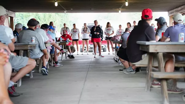 YSU head women's basketball coach Melissa Jackson speaks with golfers in a pavilion with her team standing behind her after the program's 2026 golf outing.